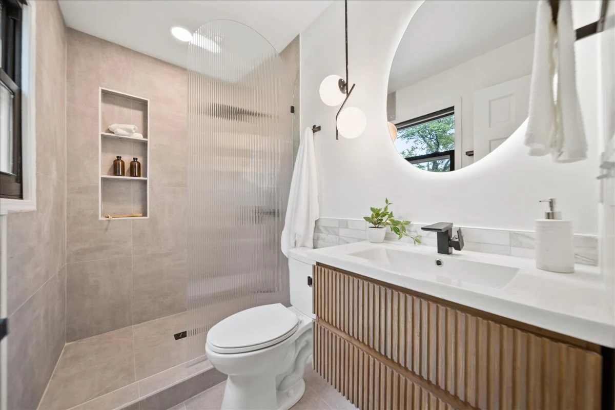 Ridgecrest bathroom with a wood vanity, round mirror, and tiled shower